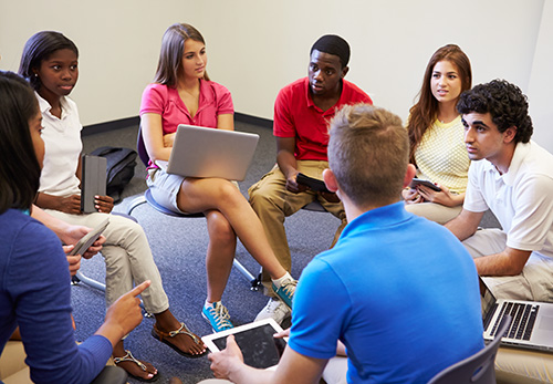 Seven students sit in a circle to engage in conversation