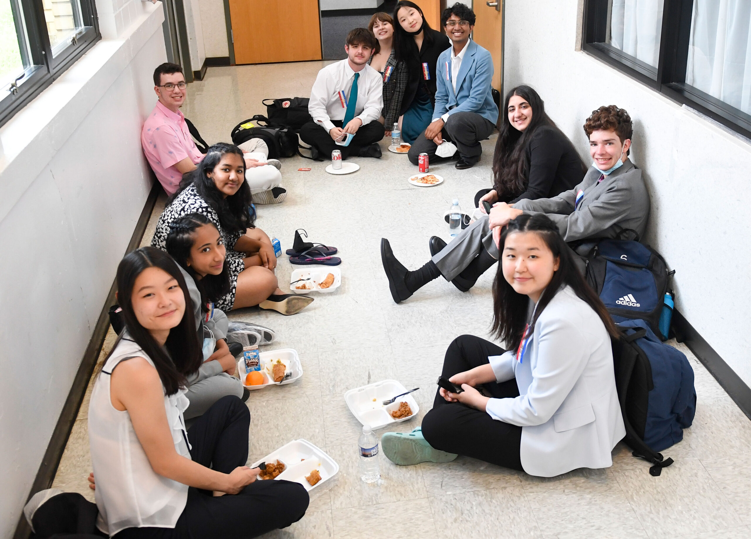 Group of students sitting in a hall at a tournament smiling at the camera